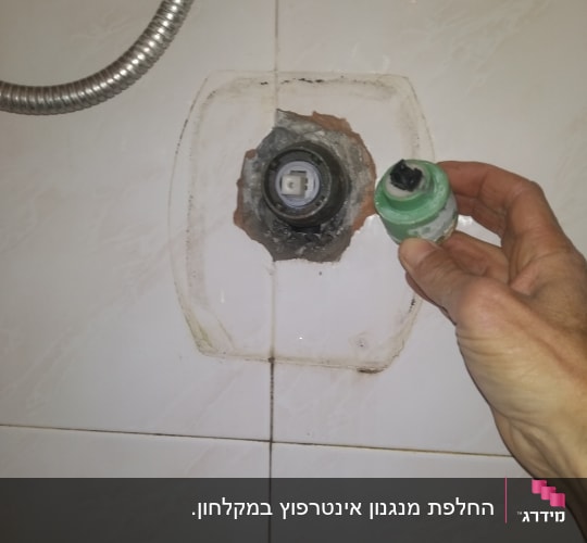 יד מחזיקה חלק אינסטלציה ליד קיר עם צינור מתכת